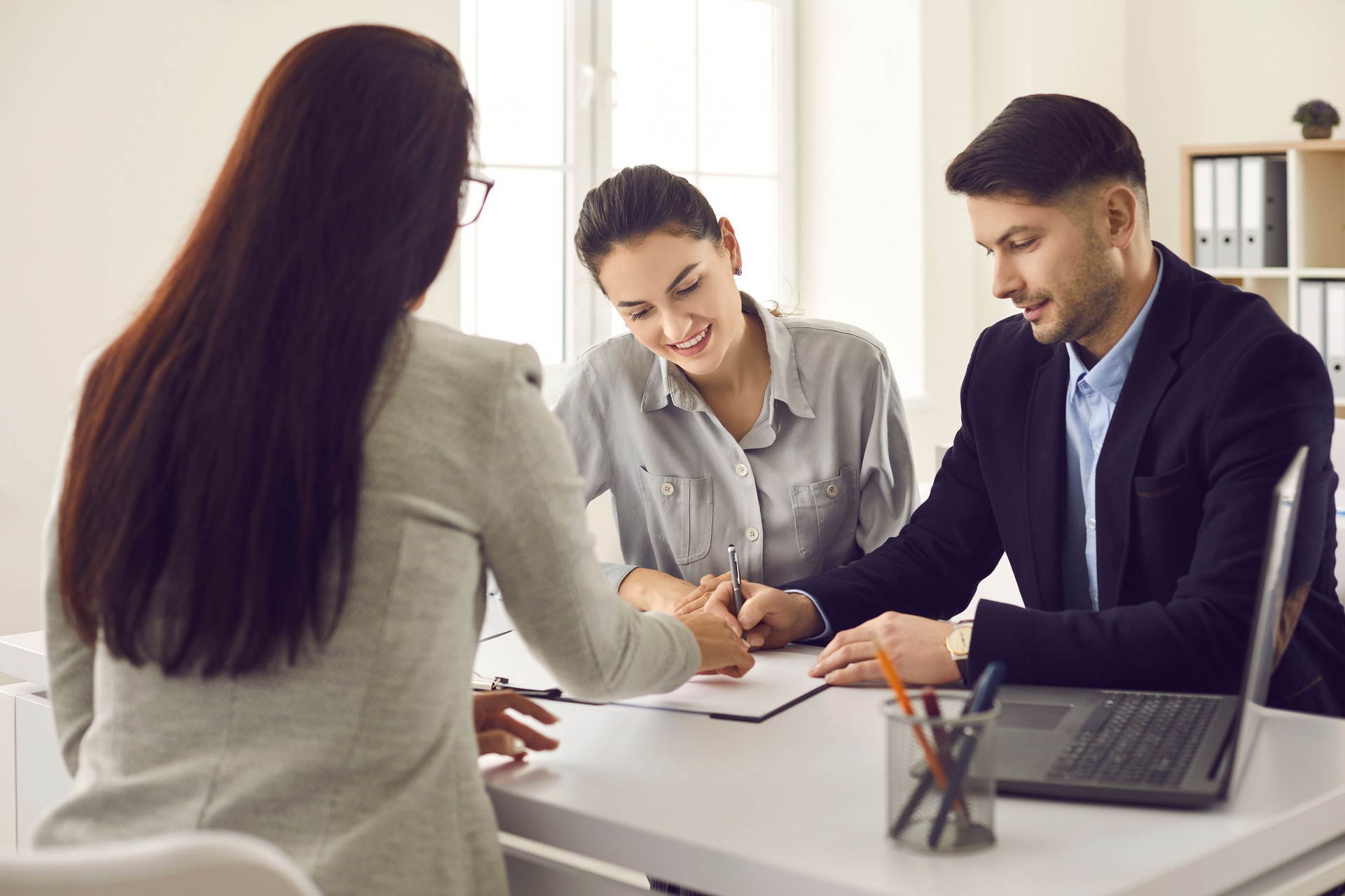 Happy couple meeting Real Estate Agent and signing lease, mortgage or house purchase agreement